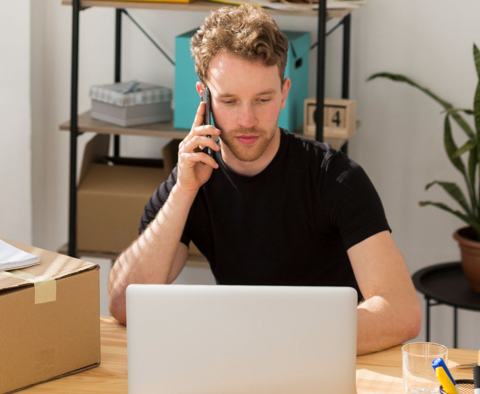 Hombre mirando su notebook mientras hablar por celular