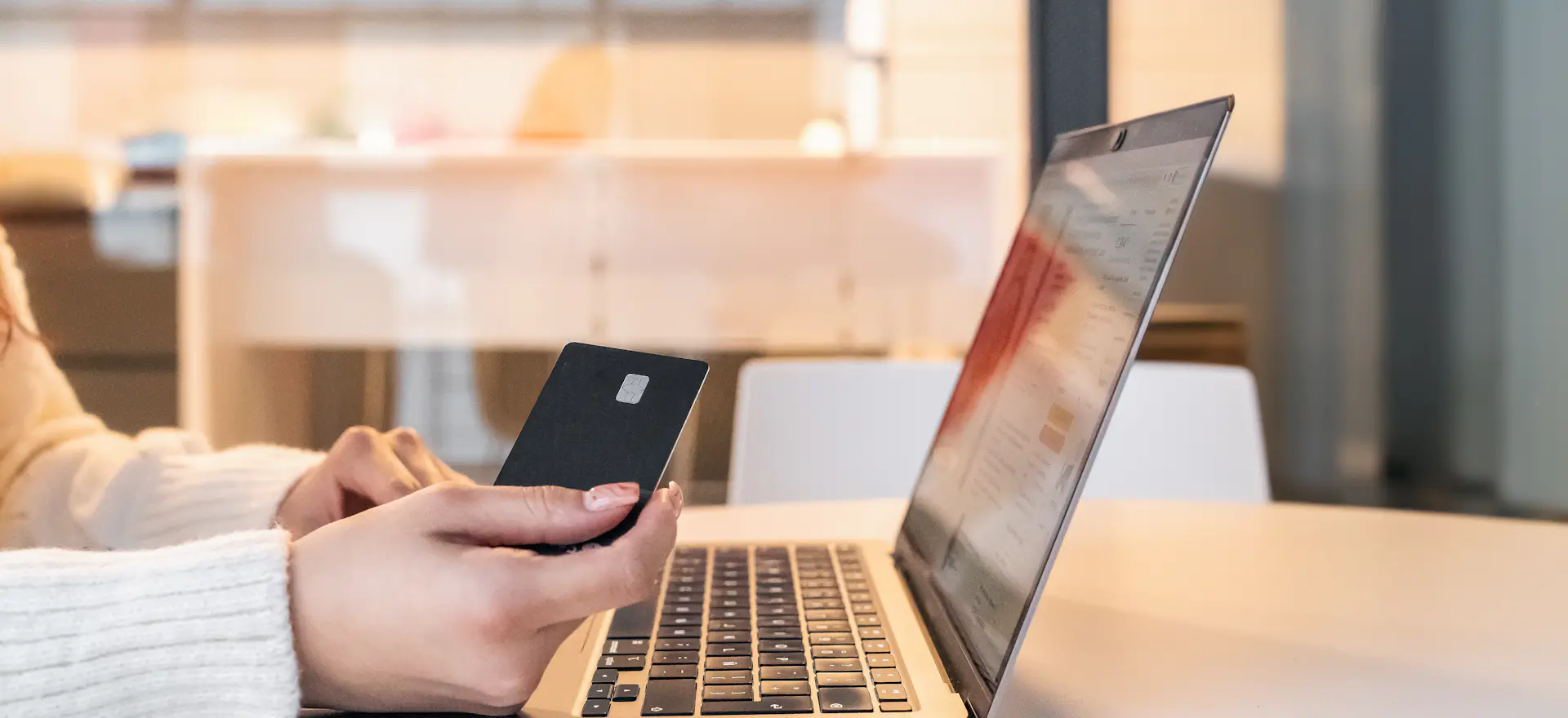 Persona pagando una compra online con tarjeta frente a una notebook